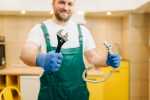 Plumber in uniform holds wrench, handyman