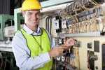 happy male caucasian technician repairing industrial machine control box