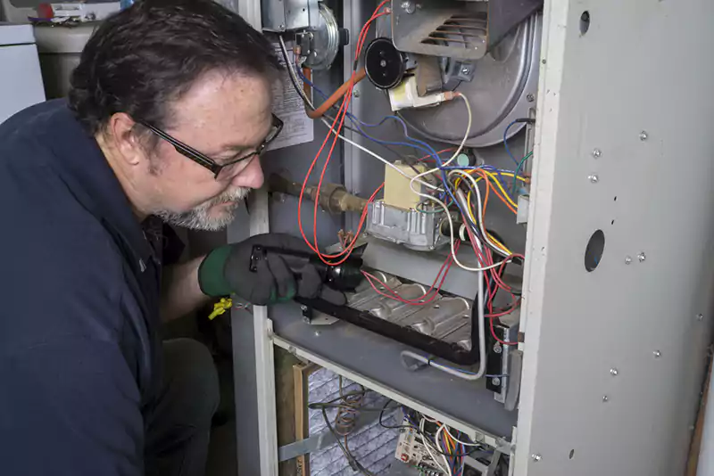Technician Looking Over A Gas Furnace Technician Looking Over A Gas Furnace